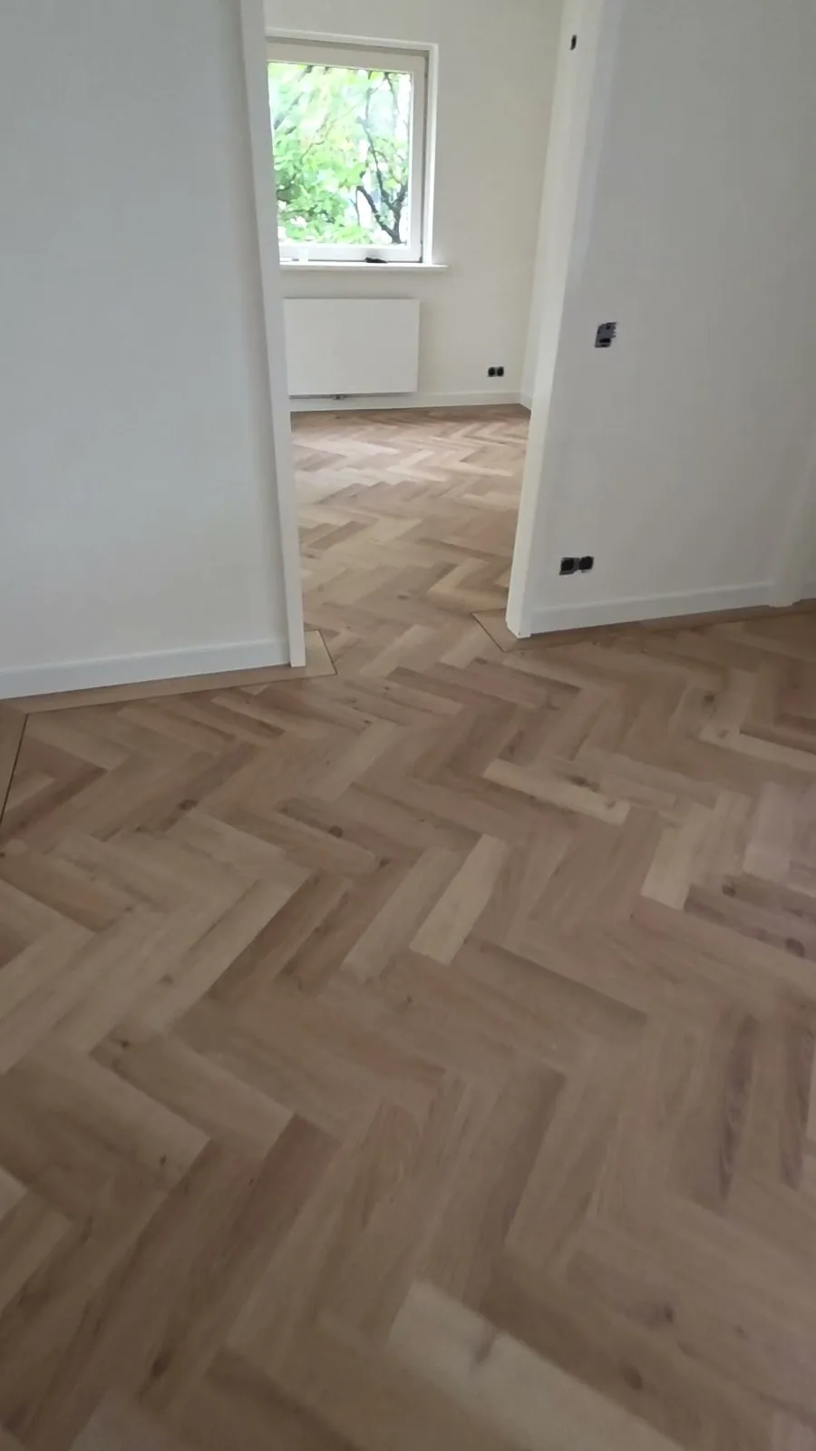 Castell-visgraatvloer die doorloopt door de doorgang naar de volgende kamer, in Amsterdam-Noord