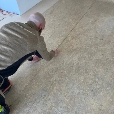 Vakman snijdt de naad tussen twee banen marmoleum uit, Harderwijk
