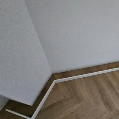 Witte plint langs een scheve wandhoek op een visgraatvloer